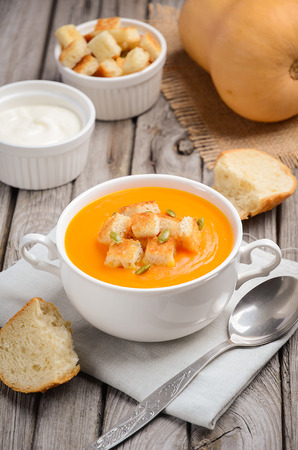 Pumpkin soup with pumpkin seeds and croutons on the wooden tableの写真素材