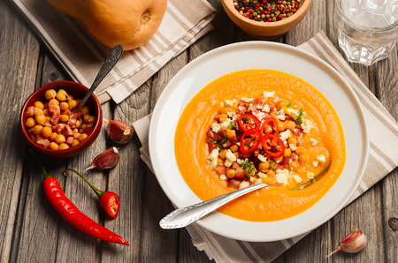 Pumpkin soup with bacon, chickpea and feta. Rustic background. Horizontal permission. Top view.の写真素材