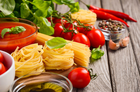 Pasta, vegetables, herbs and spices for Italian food on the rustic wooden tableの写真素材