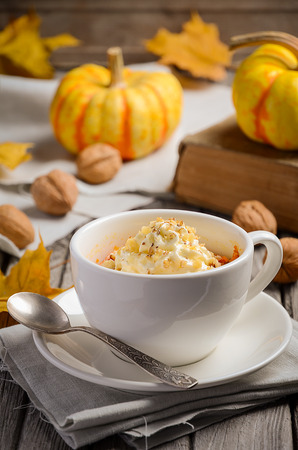 Pumpkin dessert in a mug prepared in microwave on an autumn backgroundの写真素材