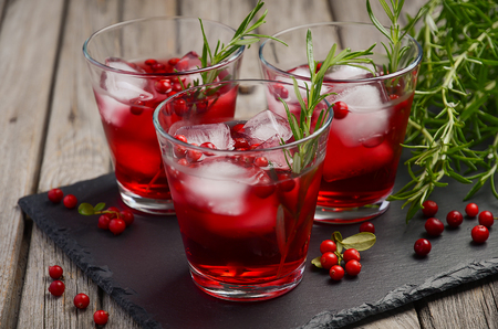 Refreshing drink with cranberries and rosemary on wooden backgroundの写真素材