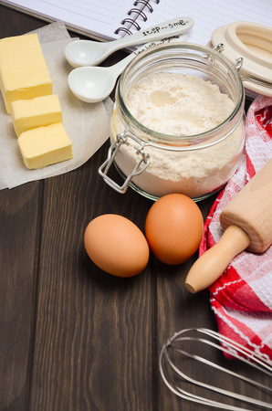 Ingredients for baking - butter, eggs and flour on dark wooden backgroundの写真素材