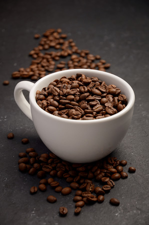 Natural organic roasted coffee beans in white cup on black background, selective focusの写真素材