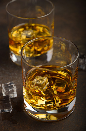 Glass of whiskey with ice on the old rusty backgroundの写真素材