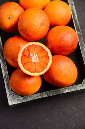 Blood oranges in wooden tray on dark backgroundの写真素材