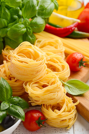 Pasta, vegetables, herbs and spices for Italian food on white wooden background, selective focusの写真素材