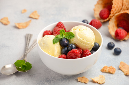 Vanilla ice cream with fresh berries on concrete background, selective focusの写真素材