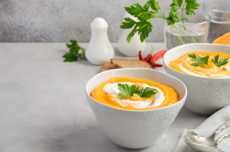 Pumpkin soup with cream and parsley on a gray backgroundの写真素材