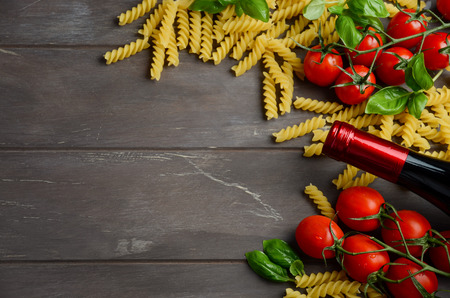 Italian food - raw fusilli, tomato, basil and wine on the wooden tableの写真素材