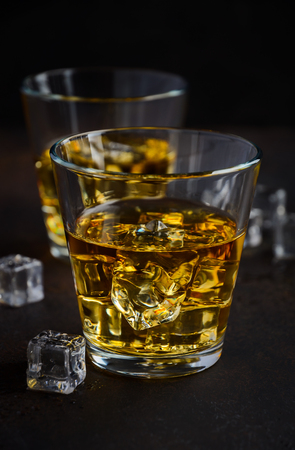 Glass of whiskey with ice on the old rusty backgroundの写真素材