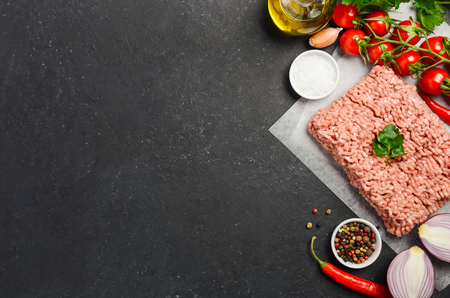 Raw minced meat on paper with fresh vegetables and spices on black background top view copy spaceの写真素材