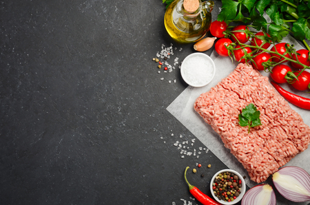 Raw minced meat on paper with fresh vegetables and spices on black background top view copy spaceの写真素材