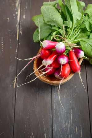Bunch of fresh colorful radishes on old rustic wooden table, selective focus.の写真素材