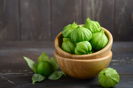 Fresh organic green tomatillos (Physalis philadelphica) with a husk on rustic wooden table.の写真素材