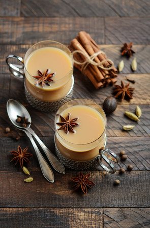 Indian masala chai tea. Spiced tea with milk in a vintage cups on the rustic wooden table.の写真素材