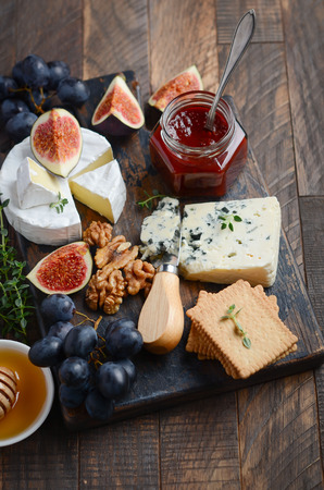 Cheese plate with grapes, figs, crackers, honey, plum jelly, thyme and nuts, selective focus.の写真素材