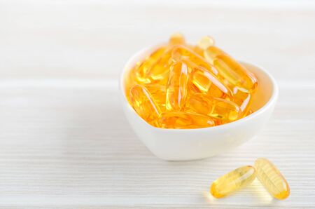 Fish oil capsules on a white wooden background, vitamin D supplementの写真素材