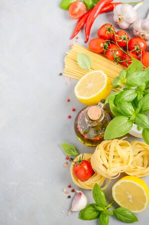 Italian food ingredients - pasta, tomatoes, basil and olive oil on gray concrete background.の写真素材