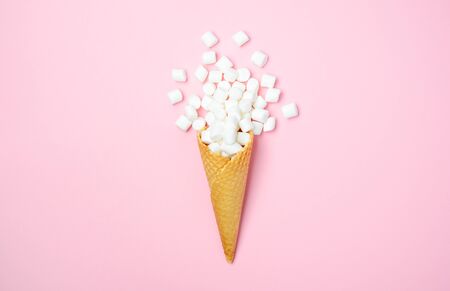Waffle cone with white mini marshmallows on a pink background Top view Flat lay Copy spaceの写真素材