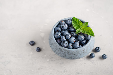 Ripe sweet blueberries in blue bowl on a gray concrete background.の写真素材