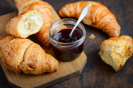 Fresh croissants with jam on a wooden board.の写真素材