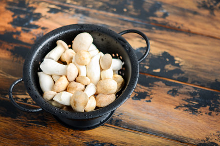 Fresh raw Eringi or King Trumpet mushrooms  in a colander on a wooden table.の写真素材