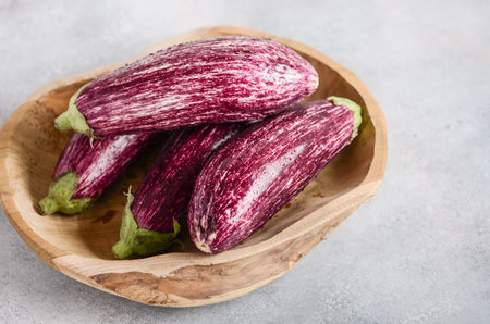 Fresh organic Graffiti eggplants in a wooden bowl on a concrete background.の写真素材