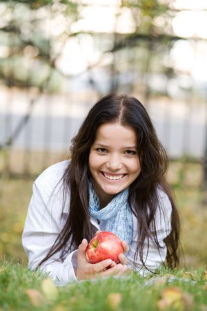 Woman with apple autumn outdoors at city parkの写真素材