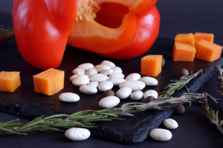 View on white bean grains. Nearby are carrot cubes, and a large, red bell pepper at the back. Ingredients for cooking homemade and wholesome food. Healthy eating conceptの写真素材