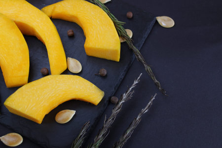 open space and top view on the pumpkin slices, which lies on a dark dish. Blur effect.Ingredients for cooking homemade and wholesome food. Healthy eating conceptの写真素材