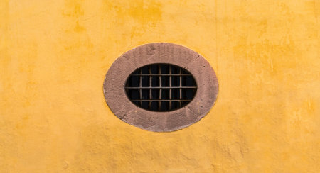 Mexican colonial oval peculiar window with yellow wall in San Miguel de Allende Mexico