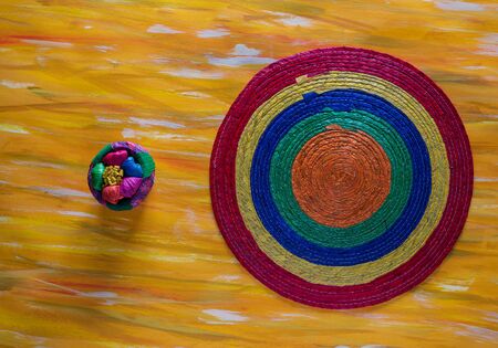Mexican Hand-woven Round Tablecloth on Yellow Surface.の写真素材