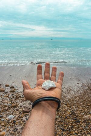 Hand Male Holding a Seashell on Virgin Mexican Beach.の写真素材