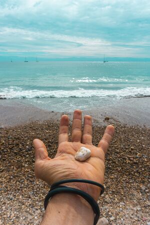 Hand Male Holding a Sea Stone on Virgin Mexican Beach.の写真素材