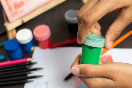 Close-up of child's hands drawing with watercolor paints.
