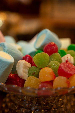 Colorful candies in a bowl on a wooden table. Selective focus.