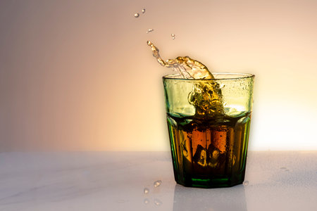 whiskey splashing into glass with ice cubes on white background