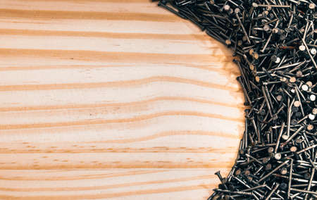 A set of nails piled up in a light wooden plank in a circle shape.の写真素材