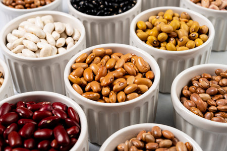 Assortment of beans in pots on gray background.