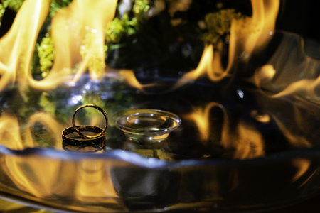 Gold ring on glass with fire in the background.の写真素材