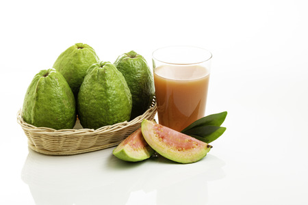 A basket full of brazilian red guavas and glass with fruit juice and pieces. Copy Space.の写真素材