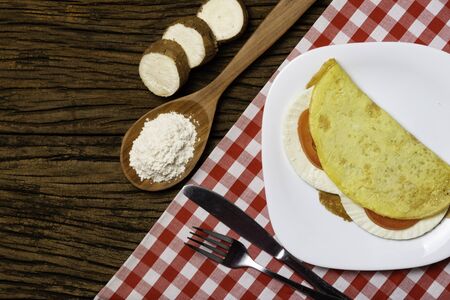 Crepioca. Pancake of cassava (tapioca) with cheese and tomato on plate on old wooden background. Selective focus.の写真素材