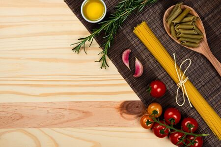 Composition with different types of pasta on pine wood background. Space for text.の写真素材