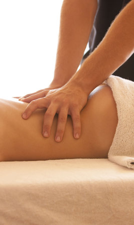  Woman lying on massage table with the hands of male masseuse on her back