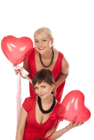 Two beautiful girls with red heart balloon over whiteの写真素材