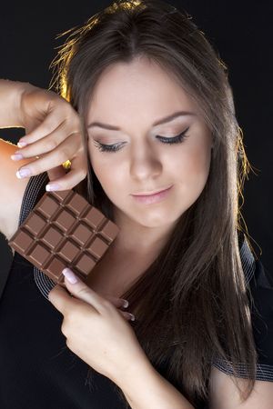 portrait of beautiful girl with a chocolate on a black backgroundの写真素材