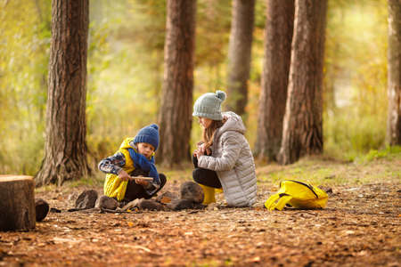 Boy and a girl are lighting a fire in the forest.の写真素材