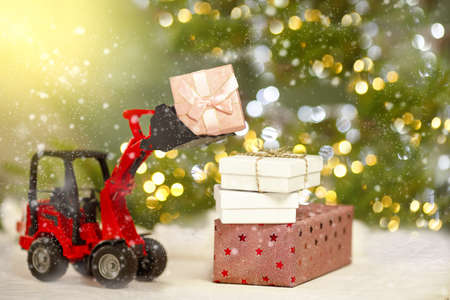 Tractor loads boxes with gifts on the background of a Christmas tree and a side from a garlandの写真素材