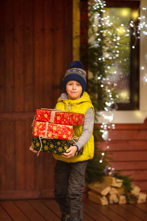The boy is holding New Year's gifts in his hands. The house is decorated for Christmas.の写真素材