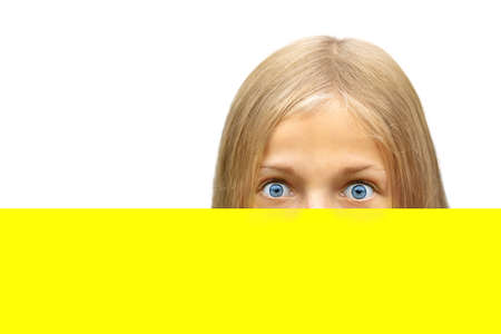 Girl with blue eyes covered part of her face with a bright yellow sheet of paper. Isolate on a white backgroundの写真素材